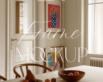 May include: A white dining room with a wooden table and chairs. There are two framed paintings on the wall, one with a vase of orange flowers and the other with abstract shapes. A bowl of fruit sits on the table.