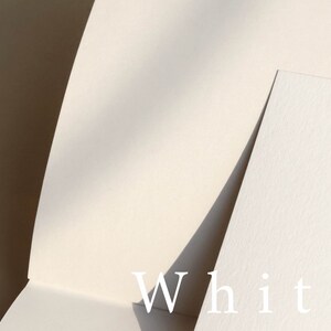 May include: Two pieces of white paper, one on top of the other, with the word "White" printed in white on the bottom piece of paper.