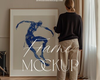 May include: A framed artwork featuring a blue abstract figure in a dance pose. The frame is on a wooden floor, and a person is standing behind it, looking at the artwork. The text "Frame Mockup" is superimposed on the image.