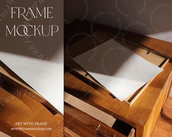 May include: A wooden frame mockup with a white paper insert. The frame is sitting on a wooden table with a drawer. The text "FRAME MOCKUP" is visible in the top left corner of the image. The text "ART WITH FRAME" and the website address "artwithframemockup.com" are visible in the bottom left corner of the image.