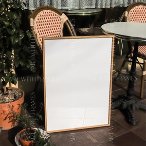 May include: A white sign with a wooden frame sits on a tiled floor in front of two wicker chairs and a table with a white tabletop. The sign is blank and ready for text. The sign is in front of a window with a sheer curtain. The text "Croissant Fruit dessert" is written in cursive above the sign.