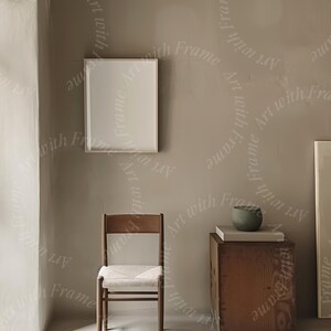 May include: A light brown wooden chair with a woven seat and a white frame sits in a room with a light brown wall. A white picture frame hangs on the wall. A small wooden box with a green bowl on top sits on the floor.