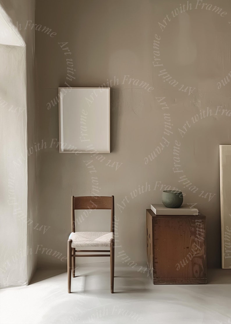 May include: A light brown wooden chair with a woven seat and a white frame sits in a room with a light brown wall. A white picture frame hangs on the wall. A small wooden box with a green bowl on top sits on the floor.