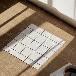 May include: A white gridded paper mockup on a wooden surface with a cup of coffee and a stack of books. The paper is in the center of the image and the coffee cup is in the lower right corner.