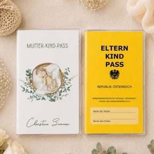 May include: Two baby books, one white and one yellow, with text and illustrations. The white book says "MUTTER-KIND-PASS" and has a baby illustration. The yellow book says "ELTERN KIND PASS". Crochet baby shoes and flowers are also in the image.