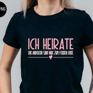 Peut inclure: T-shirt noir avec un texte rose qui dit "Ich heirate die anderen sind nur zum feiern hier" avec un symbole de cœur rose.