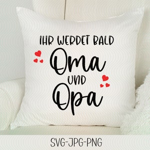 May include: White pillow with red hearts and black text that reads "Ihr werdet bald Oma und Opa".