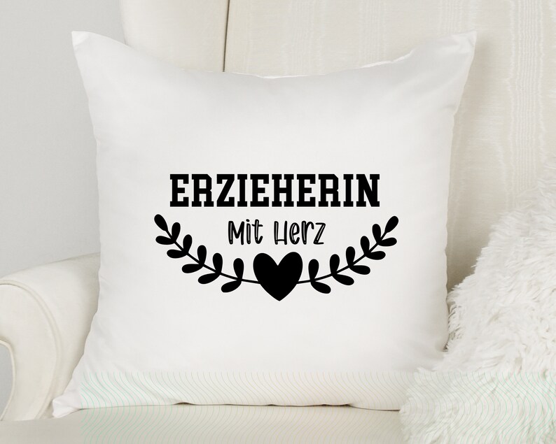 May include: White pillow with black text that reads "ERZIEHERIN Mit Herz" and a black heart.