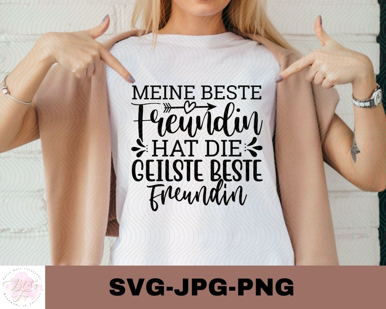 Op de afbeelding: Wit T-shirt met zwarte tekst die "Meine beste Freundin hat die geilste beste Freundin" luidt, met een klein hartje en pijl boven het woord "Freundin".