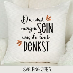 May include: White pillow with black text that reads "Du wirst morgen sein was du heute DENKST". The text is in a cursive font and has a decorative flourish above the word "sein".