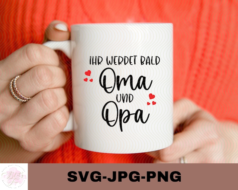 May include: White ceramic mug with black text that reads "Ihr werdet bald Oma und Opa" with red hearts around the text.