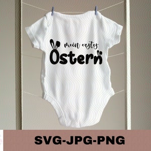 May include: White baby onesie with black text that reads "mein erstes Ostern" and a black bunny ear graphic.