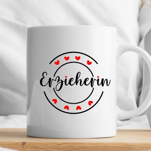 May include: White ceramic mug with a black circle and the text "Erzieherin" in black script. The circle is decorated with red hearts.