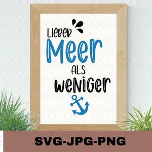May include: A framed print with the text "Lieber Meer als weniger" in black lettering on a white background. A blue anchor symbol is below the text. The frame is light brown wood.