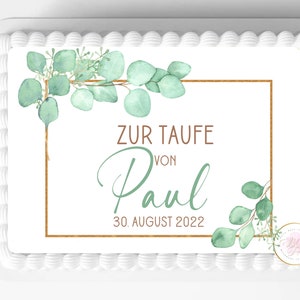 Puede incluir: Pastel blanco con hojas verdes de eucalipto y marco dorado. El texto en el pastel dice "Zur Taufe von Paul 30. August 2022".