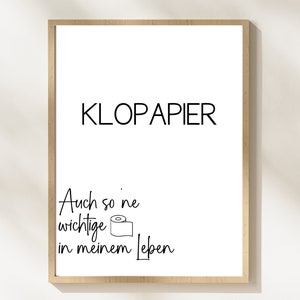 Op de afbeelding: Een ingelijst print met de tekst "KLOPAPIER" en de zin "Auch so 'ne wichtige in meinem Leben" met een tekening van een rol toiletpapier.