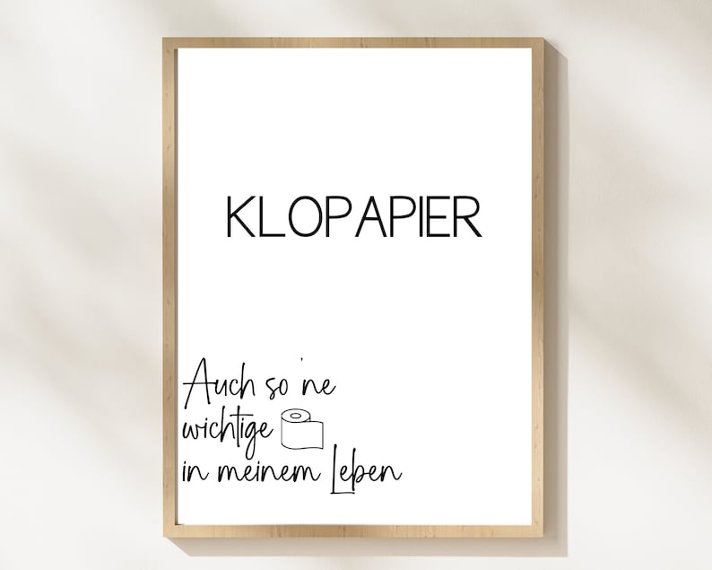 Op de afbeelding: Een ingelijst print met de tekst "KLOPAPIER" en de zin "Auch so 'ne wichtige in meinem Leben" met een tekening van een rol toiletpapier.