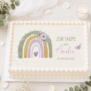 Könnte beinhalten: Ein rechteckiger Blechkuchen mit weißer Glasur und dekorativem Rand. Auf der Oberseite befindet sich ein Druckmotiv mit einem salbeigrünen, gelben und lavendelfarbenen Regenbogen, lila Blumen, einem Herz, einem Schmetterling sowie dem Text ZUR TAUFE VON Amelie 30. AUGUST 2022.