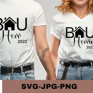 May include: Two white t-shirts with black text and a house graphic. The text on the shirts reads "BAU" and "Herrin 2022".