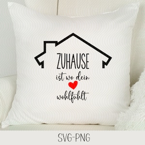 May include: White pillow with black text that reads "Zuhause ist wo dein wohlfühlt" with a black house outline and a red heart in the middle of the text.