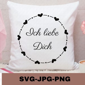 May include: White pillow with black text that reads "Ich liebe Dich" surrounded by a circle of black hearts.
