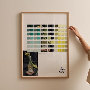 May include: A framed print featuring a Pantone color chart with shades of green and yellow. A smaller image shows a bottle and flowers. The text "Love in Color 5" is in the lower right corner. The frame is a light brown color.