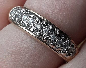 May include: A gold band ring with a row of small, clear diamonds set in the metal.