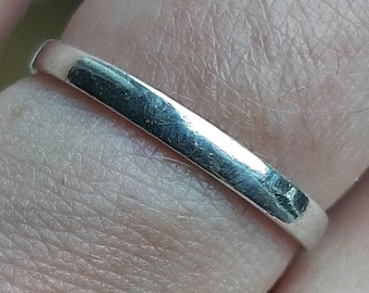 Puede incluir: Un anillo de banda de plata usado en un dedo.
