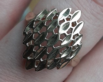 May include: A gold ring with a square-shaped design featuring a delicate, intricate pattern of overlapping leaves.
