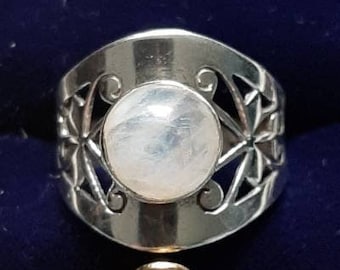 May include: A silver ring with a white moonstone set in a filigree design. The ring is in a blue velvet ring box.