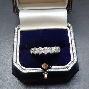 May include: A diamond eternity band ring in a blue velvet ring box. The ring is set with round brilliant diamonds.