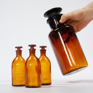 Conjunto de 4 botellas de boticario vintage de vidrio marrón ámbar con tapones de vidrio originales. Decoración del hogar en estilo industrial. utensilios de cocina antiguos