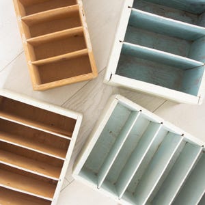 May include: Four wooden storage boxes with dividers. Two boxes are painted a light blue color and two boxes are painted a natural wood color.