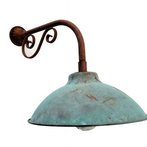 May include: A rusty metal outdoor wall light fixture with a green, weathered, dome-shaped shade.
