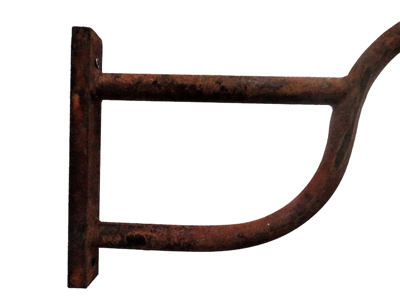 May include: A rusty metal wall-mounted hook with a curved arm. The hook is designed to hold items like coats, hats, or towels.