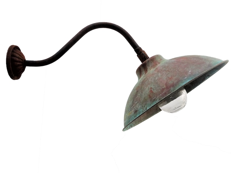 May include: A rustic, copper-toned outdoor wall light with a curved arm and a rounded shade. The light has a clear glass bulb.