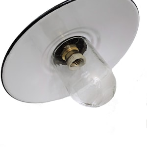 May include: White enamel ceiling light fixture with a black rim and a clear glass shade. The fixture has a standard light bulb socket.