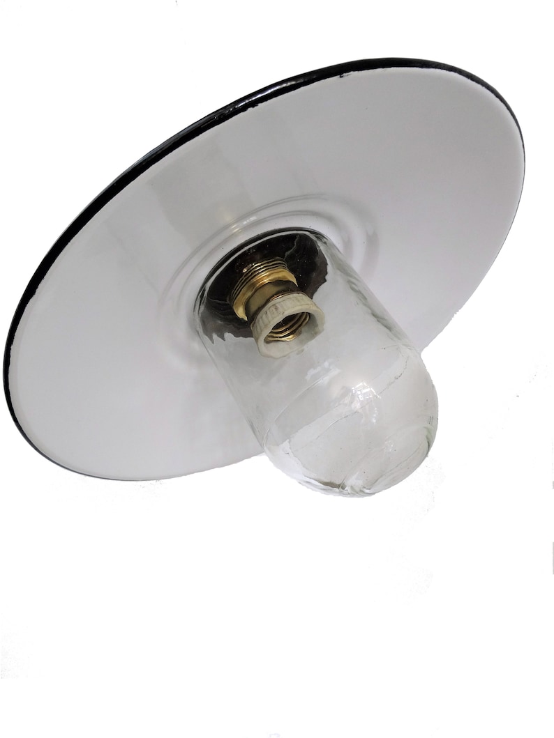 May include: White enamel ceiling light fixture with a black rim and a clear glass shade. The fixture has a standard light bulb socket.
