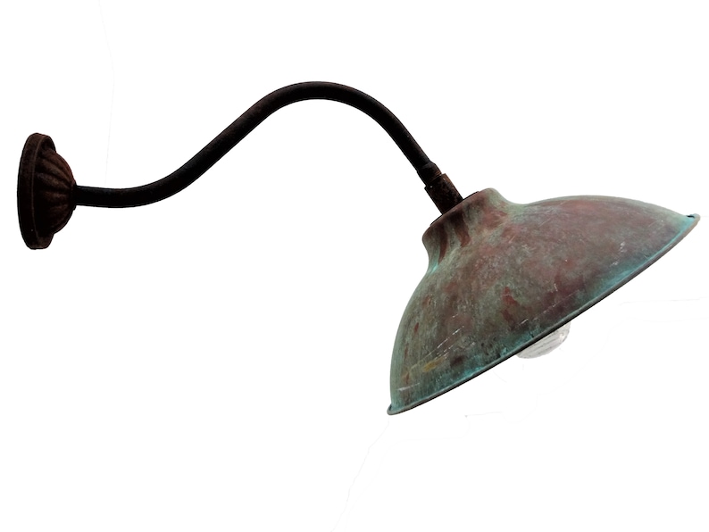 May include: A vintage-style wall-mounted light fixture with a curved arm and a copper-colored shade. The shade has a weathered patina and a light bulb is visible inside.