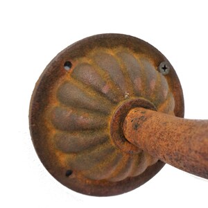 May include: A rusty metal pipe with a decorative, fluted, round cap. The cap has a screw hole and a small, round hole. The pipe is attached to the cap.