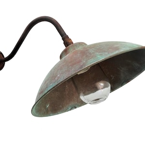 May include: A vintage copper outdoor wall light fixture with a curved arm and a domed shade. The light is weathered and has a green patina.