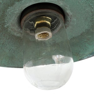 May include: A close-up of a green metal lampshade with a clear glass globe and a brass light socket.