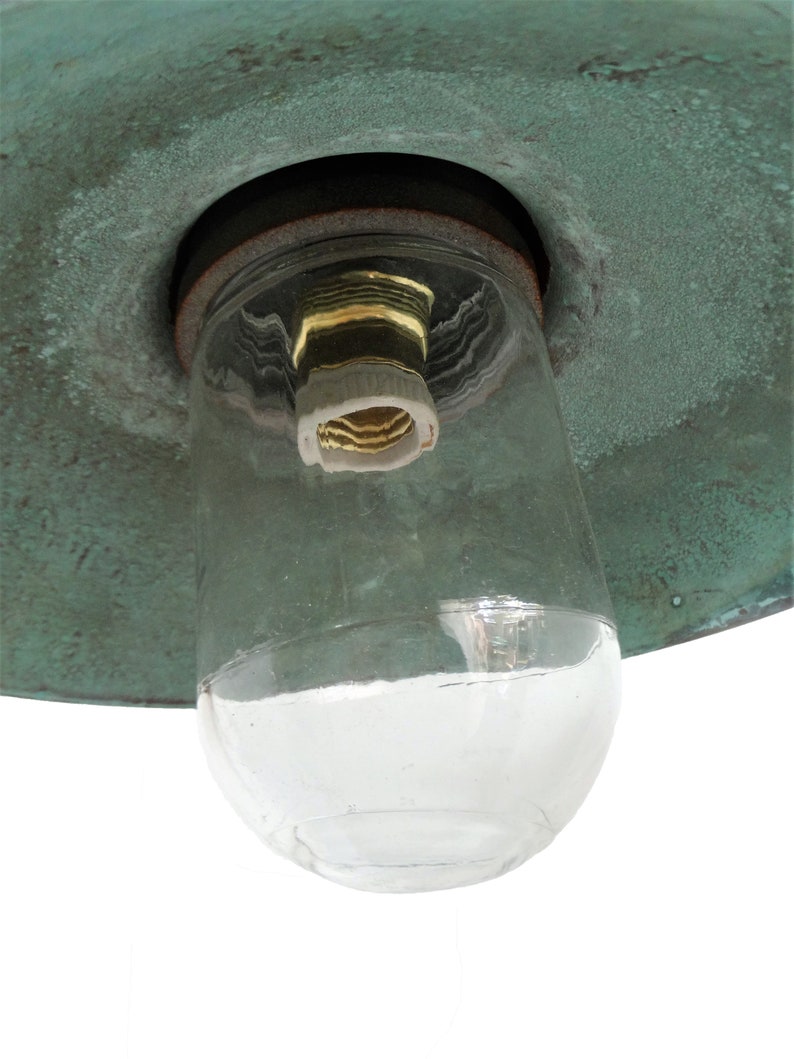 May include: A close-up of a green metal lampshade with a clear glass globe and a brass light socket.