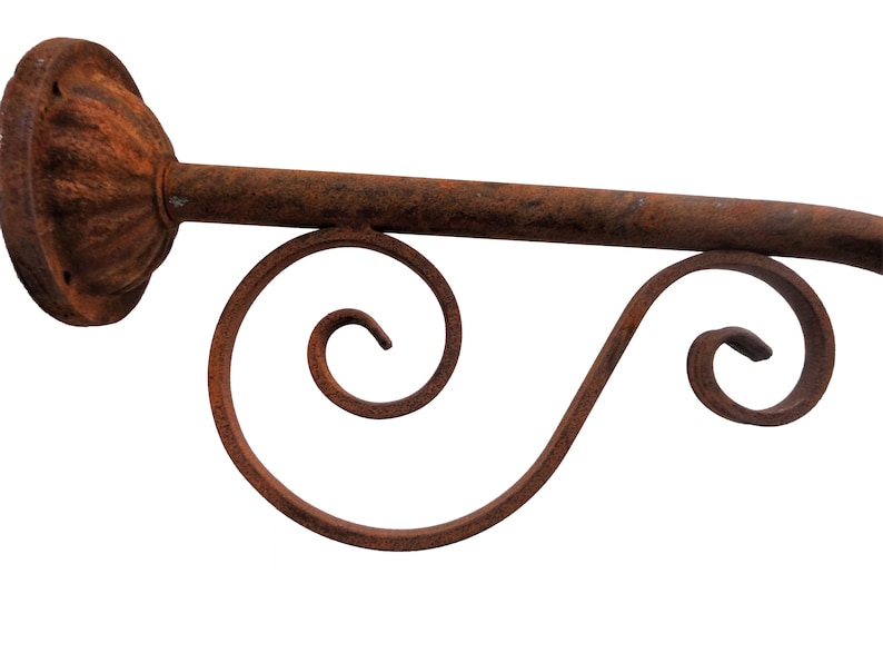 May include: Rustic metal wall mount with a decorative scroll design. The mount is made of iron and has a rusty finish.