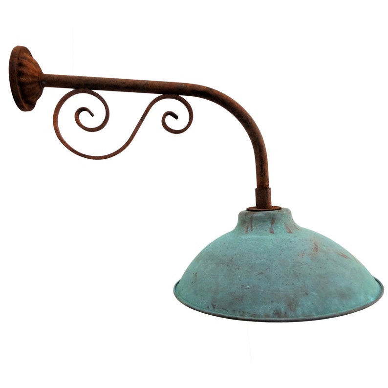 May include: A vintage-style wall-mounted light fixture with a curved arm and a green metal shade. The arm features a decorative scroll design and is made of rusty metal.
