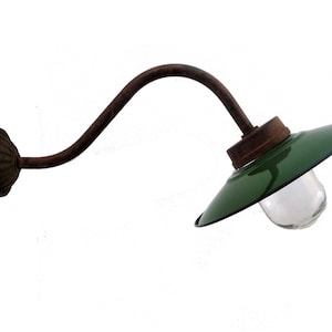 May include: A vintage green metal wall sconce with a curved arm and a clear glass globe. The sconce has a rusty finish and is perfect for adding a touch of industrial style to any room.