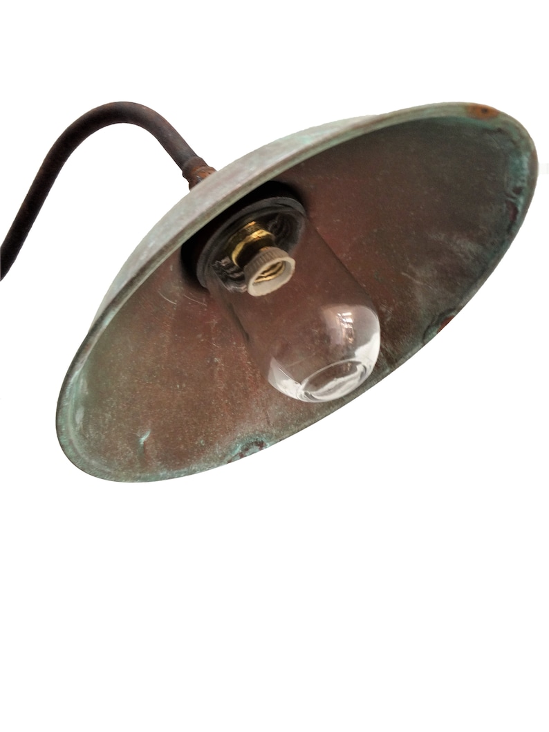 May include: A vintage copper outdoor light fixture with a clear glass bulb. The light fixture has a curved arm and a rounded shade.