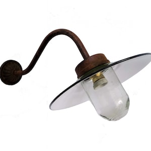 May include: A rusty metal wall sconce with a curved arm and a clear glass globe light fixture. The sconce has a round, decorative base and a flat, circular glass shade.