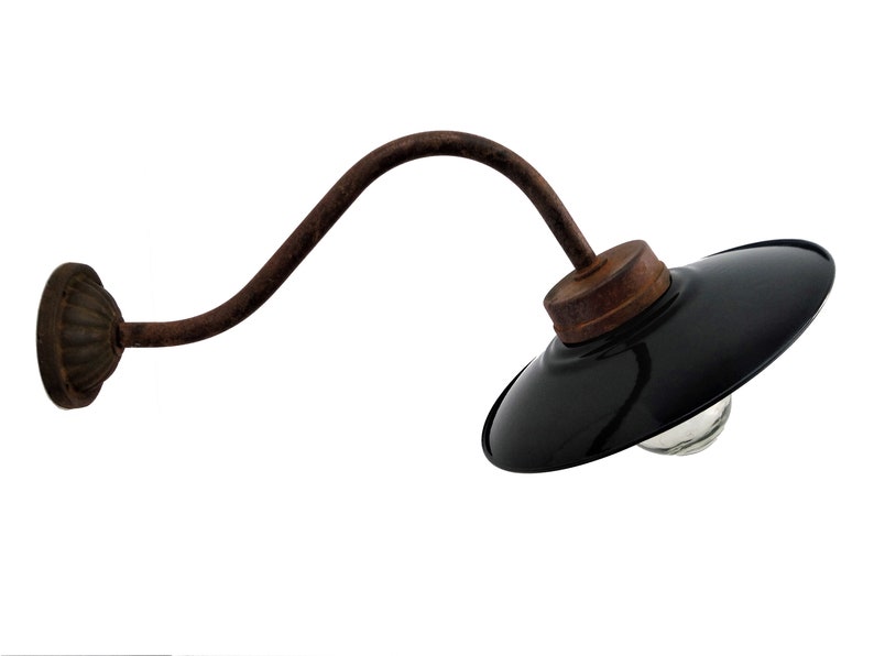 May include: A black metal wall sconce with a curved arm and a black enamel shade. The sconce has a rustic, industrial look and is perfect for adding a touch of vintage style to any room.