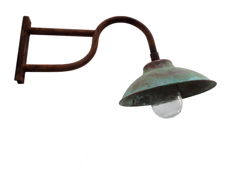 May include: A rusty metal wall-mounted light fixture with a green metal shade and a clear glass globe. The light fixture has a curved arm and a rectangular base.